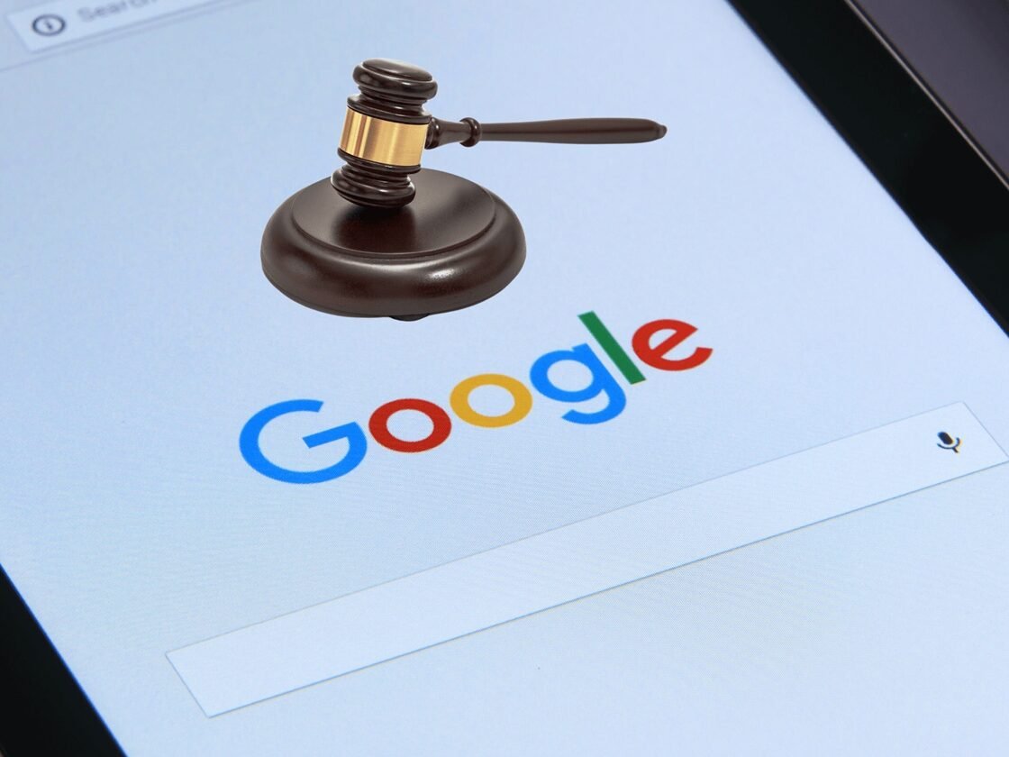 A digital tablet displays the Google search engine homepage. Superimposed on the Google logo is a wooden gavel resting on its sound block, symbolizing legal or judicial matters in the context of online search or information.
