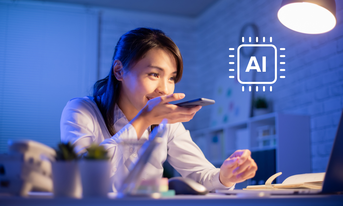 A girl in a white shirt speaks into her smartphone while working at a desk with a laptop, with an overlaid AI processor chip icon, demonstrating voice-activated artificial intelligence assistance in educational and professional settings.